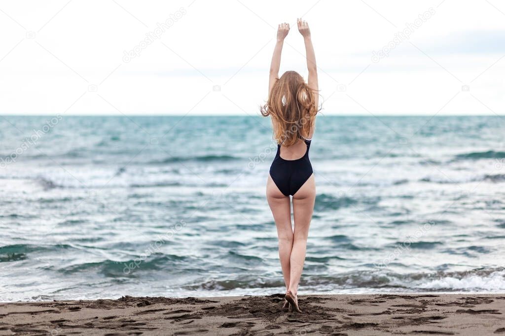 Beautiful and young blonde girl in a swimsuit relaxing on the sea with blue waves, resort
