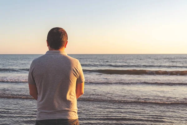 Young man meets the sunset on the beach at the sea, evening