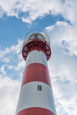 Gündüz vakti Karadeniz 'de deniz feneri, Gürcistan Poti. Kırmızı ve beyaz. Ağaçların yanındaki açık mavi gökyüzüne karşı.