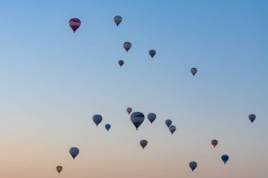 Kapadokya 'da güneş doğarken kayalık arazide uçan sıcak hava balonu. Seyahat