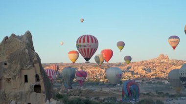 Cappadocia, Turkey - 5 August, 2025: Hot air balloons flying over rocky landscape at sunrise in Cappadocia. Travel