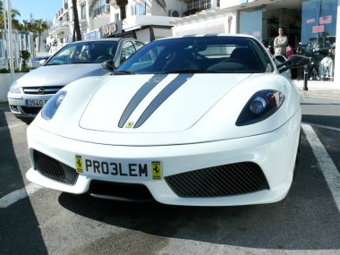 Puerto Banus, İspanya. Ocak 9, 2009. Beyaz renk iki gri çizgiler Ferrari F430 Scuderia coupe Cabrio ile önden görünümü Puerto Banus liman deniz kenarında sokakta park edilmiş. Arka plan olarak lüks mağazalar vardır
