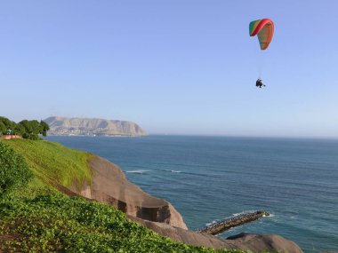 Bir yok motoru yamaçparaşütü ile iki kimliği belirsiz kişi Miraflores sahil turistik ilçe Lima üzerinde Peru uçuyor.