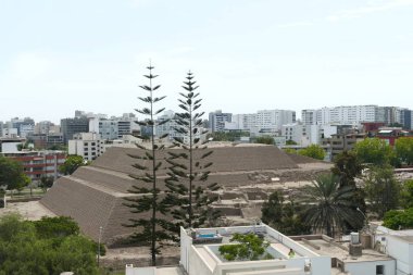 Partial view of the ancient pyramid temple called Huaca Huallamarca. This important archaeological complex is located in the center of the San Isidro district of Lima surrounded by modern buildings and houses clipart