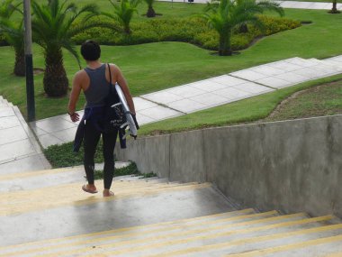 Sörfçü bir plaj Miraflores bölgesinde Lima, Peru için bir merdiven onun surfboard ile azalan