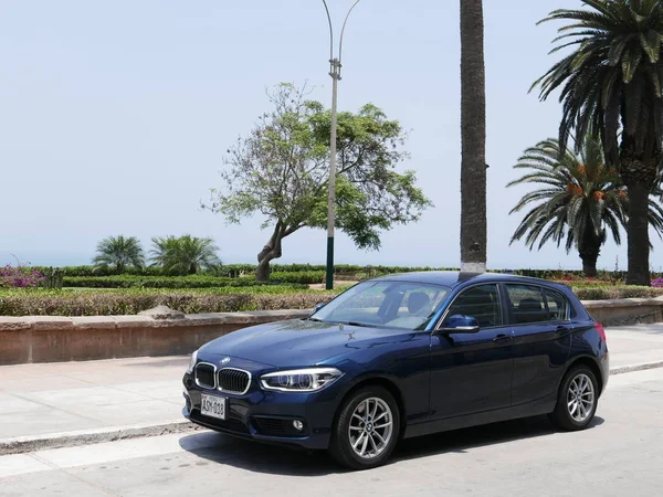 Lima, Peru. 12 Ekim 2017. Alman otomobil Park Lima Barranco bölge bir mavi nane koşulu Bmw 120i dört kapı önünde ve görüntüleyin. Arka planda çiçekler, bitkiler ve ağaçlar, kıyı şeridi ile bir park var