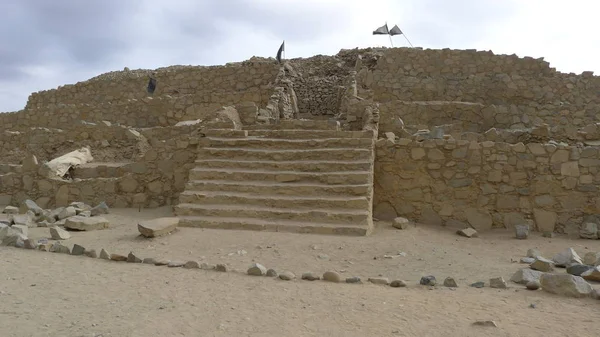 Stone pyramid with a staircase, a pedestrian way and a clear sky with some clouds in Caral.  Here, in this desert, was the capital of Caral Civilization with about 5000 years old and is the first civilization of America located at north of Lima