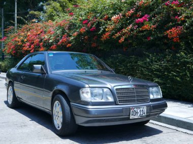 Lima, Peru. 19 Aralık 2016. 1994 yılında Daimler-Benz Ag Almanya tarafından inşa edilmiş bir gri renkli beceri durumu Mercedes-Benz E320 Sportline Coupe görünümü. Bu fotoğraf güneşli bir günde çekildi. Begonvillerin, yaya yolu ve sokak görüntü vardır