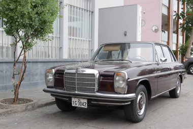 Lima, Peru. 11 Temmuz 2018. 1968 ve 1976 arasında Almanya'da inşa edilmiş kestane rengi bir Mercedes-Benz 200 Sedan ön ve yan görünümü. Araba temiz ve beceri durumu bu. Güneşli bir günde Lima Barranco İlçe Park edildiğini. 