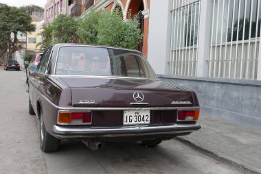 Lima, Peru. 11 Temmuz 2018. 1968 ve 1976 arasında Almanya'da inşa edilmiş kestane rengi bir Mercedes-Benz 200 Sedan arka ve yan görünümü. Araba temiz ve beceri durumu bu. Güneşli bir günde Lima Barranco İlçe Park edildiğini. 