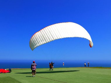 Lima, Peru. May 6, 2016. A pilot in a no engine paraglider is ready to jump and fly on the coast of Miraflores touristic district of Lima. Paragliding is a popular sport on the coast of Miraflores clipart