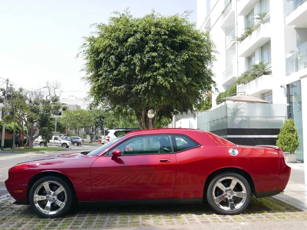 Lima, Peru. March 25, 2017. Side view of a red mint condition Dodge Challenger SRT8 392 Hemi with a V8 engine parked in Miraflores touristic district of Lima. A housing development is as a background