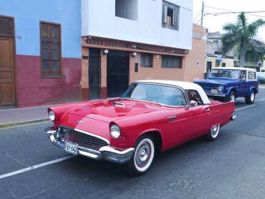 Lima, Peru. 4 Aralık 2016. 1957 yılında Ford Motor Company ABD tarafından inşa edilmiş bir V8 motoru ile ilk nesil Ford Thunderbird Coupe kırmızı ve beyaz renk ön ve yan görünümü. Mavi ve beyaz bir Ford Bronco'nun Ayrıca görüntüdür. 