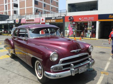 Lima, Peru. 24 Mart 2016. Ön ve yan bir Bordo renk nane ve olağanüstü durum Chevrolet De Luxe coupe General Motors tarafından 1951 yılında inşa görüntüleyin. Güzel ve güneşli bir günde bir benzin istasyonu Lima San Isidro bölge erişimi mevcuttur.  