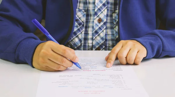 テーブルに英語のテストを取って青のペンを持っている手 — ストック写真