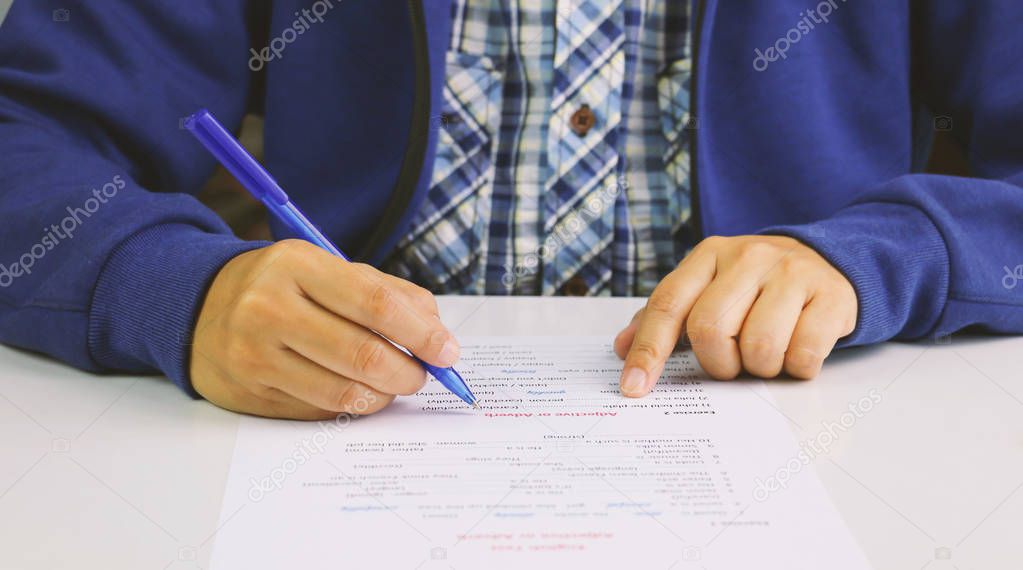 hand holding blue pen taking English test on table
