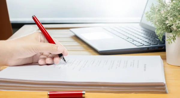 Mano sosteniendo pluma roja sobre texto borroso — Foto de Stock