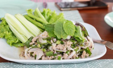 Baharatlı domuz salatasını beyaz tabakta sebzeyle kapat.