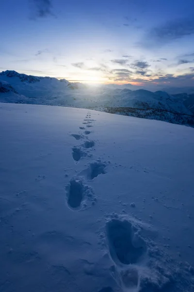Human footprints in the snow before sunrise on the summits of the mountains. Dachstein, Autria, Europe.