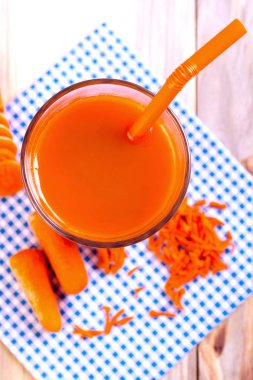 Taze havuç suyu ile mavi peçeteye kokteyl tübül şeffaf cam. Kavram sağlıklı içecek. Üstten görünüm. Dikey. Yakın çekim.