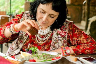 Yetişkin şık kadın gıda tuz ile sprinkles veya açık havada Restoran yemeğine biber. Tuz ekleyerek. Seçici odak. Yakın çekim.