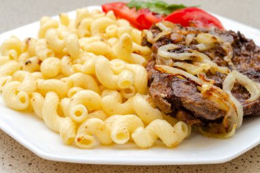 Kızarmış domuz eti veya sığır eti ve beyaz sos ile ev yapımı makarna pişmiş, beyaz bir tabak üzerinde yalan. Ev yapımı iştah açıcı yemek kavramı. Selctive odak. Yakın çekim.