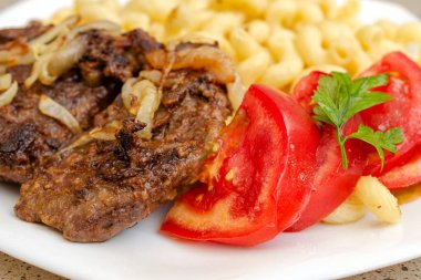 Kızarmış domuz eti veya sığır eti ve beyaz sos ile ev yapımı makarna pişmiş, beyaz bir tabak üzerinde yalan. Ev yapımı iştah açıcı yemek kavramı. Selctive odak. Yakın çekim.