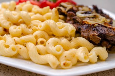 Kızarmış domuz eti veya sığır eti ve beyaz sos ile ev yapımı makarna pişmiş, beyaz bir tabak üzerinde yalan. Ev yapımı iştah açıcı yemek kavramı. Selctive odak. Yakın çekim.