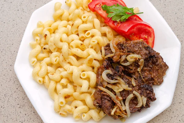 Kızarmış domuz eti veya sığır eti ve beyaz sos ile ev yapımı makarna pişmiş, beyaz bir tabak üzerinde yalan. Ev yapımı iştah açıcı yemek kavramı. Selctive odak. Üstten görünüm. Yakın çekim.
