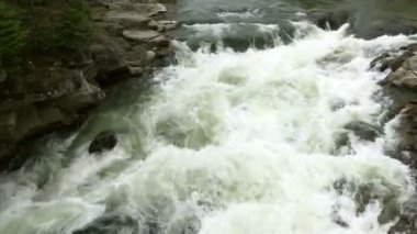 Açık nehir su akışı sıçraması ile beyaz ve şeffaf kabarcıkları ile akan. Güçlü şelale river rapids üzerinde. Video 4k. Yakın çekim.