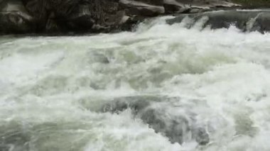 Açık nehir su akışı sıçraması ile beyaz ve şeffaf kabarcıkları ile akan. Güçlü şelale river rapids üzerinde. Video 4k. Yakın çekim.