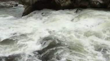 Açık nehir su akışı sıçraması ile beyaz ve şeffaf kabarcıkları ile akan. Güçlü şelale river rapids üzerinde. Video 4k. Yakın çekim.