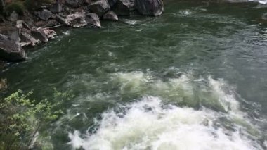Açık nehir su akışı sıçraması ile beyaz ve şeffaf kabarcıkları ile akan. Güçlü şelale river rapids üzerinde. Video 4k. Yakın çekim.