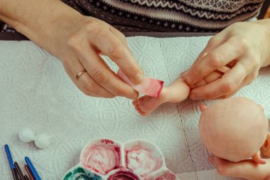 Kadın el bebek Bjd veya yeniden doğmuş işyerinde yapacaklar. İşlenecek parçanın işleniyor. Bebek ana üretici sanatı kavramı. Seçici odak. Yakın çekim.