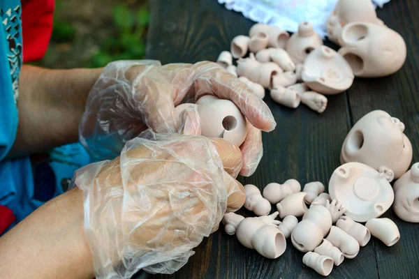 Female hands make dolls of BJD in the workplace. Processing the workpiece. The concept of the craft of the master manufacturer of dolls. Selective focus. Close-up.