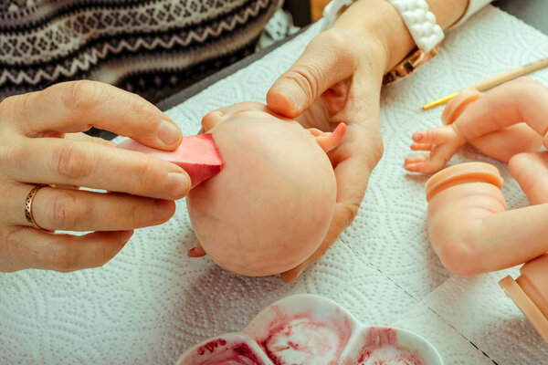 Женские руки делают куклы BJD или возрождаются на рабочем месте. Обработка заготовки. Концепция ремесла мастера-производителя кукол. Выборочный фокус. Крупный план
.