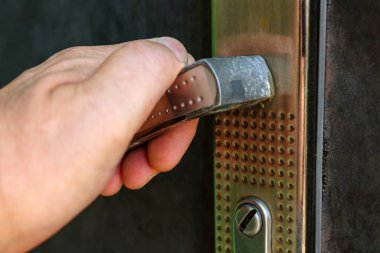 İnsan el presleri eski metal kapı kolu aşağı. Yakın çekim.