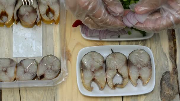 Preparation of a homemade snack from smoked mackerel. Hands lay out the smoked fish from the package in a dish and decorate the food with onions. — Stock Footage Preparation Homemade Snack Smoked Mackerel Hands Lay Out Smoked Fish Stock Video