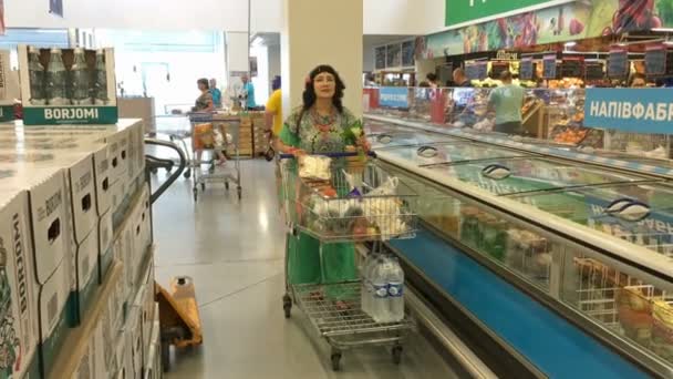 キエフ ウクライナ 2018年 大人でエレガントな女性がスーパーで品物を持つ行の間に購入するとショッピングカートを運ぶ楽しみにしています ショッピング概念 — ストック動画