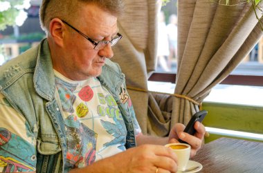 Kafede otururken onun akıllı telefon kullanan yakışıklı komuta sizde portresi. Yakın çekim.