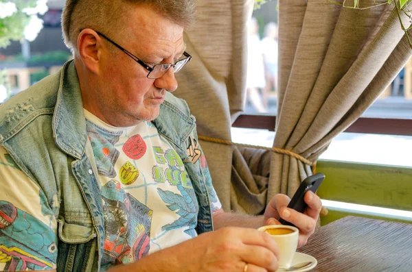 Kafede otururken onun akıllı telefon kullanan yakışıklı komuta sizde portresi. Yakın çekim.