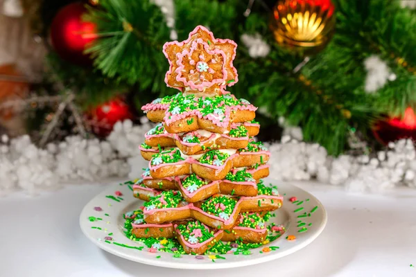 Gingerbread herringbone at white dish against the background of the Christmas tree. Close-up.