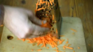 El ahşap mutfak tahtada metal rende kullanarak havuç kesim.