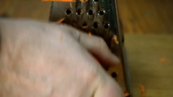 Menschenhände Schneiden Möhren Mit Einer Metallreibe Auf Einem Hölzernen Küchenbrett — Stockvideo