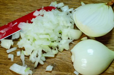 Kırmızı bıçak, yarım soğan ve ince dilimlenmiş soğan ahşap mutfak gemide yalan. Yemek yemek. Yakın çekim.