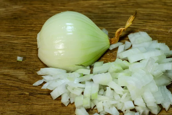 Onion cut in half and finely crumbled onion lie on wooden kitchen board. Cooking food. Close-up.
