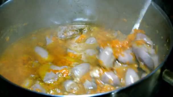 Cooking homemade food. Goulash or thick soup of chicken giblets with carrots boils in a saucepan. It is stirred with a metal spoon. — Stock Footage Cooking Homemade Food Goulash Thick Soup Chicken Giblets Carrots Boils Stock Footage