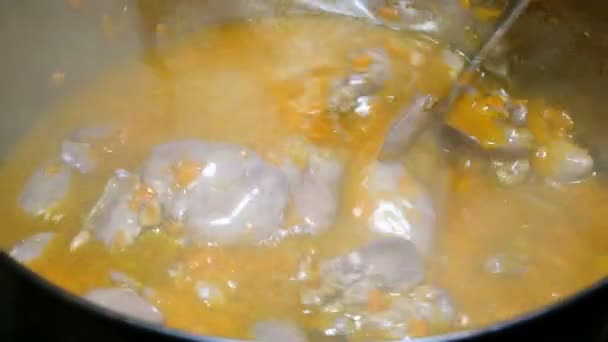 Cooking homemade food. Goulash or thick soup of chicken giblets with carrots boils in a saucepan. It is stirred with a metal spoon. — Stock Footage Cooking Homemade Food Goulash Thick Soup Chicken Giblets Carrots Boils Stock Video