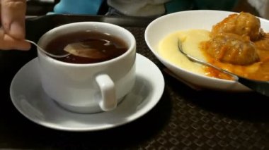 Yemek yerken çay poşeti sıcak suya daldırma çay yapıyor. Yakın çekim.