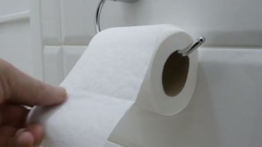 İnsan eli çok tuvalet kağıdı rulosu tuvalette alır. Üzerinde asılı duvar banyo tuvalet kağıdı.